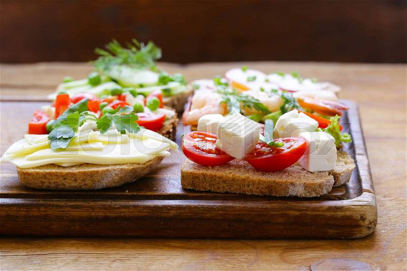 Variety of sandwiches with different fillings (avocado, shrimp, fish, ham, vegetables), stock photo