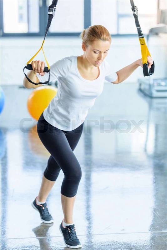 Blonde sportswoman training with resistance band in sports center , stock photo