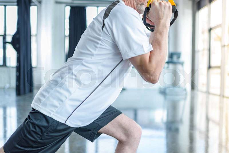 Senior sportsman training with resistance band in sports center , stock photo