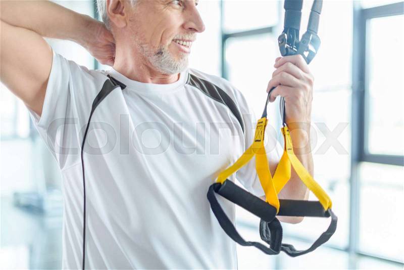 Senior sportsman training with resistance band in sports center , stock photo