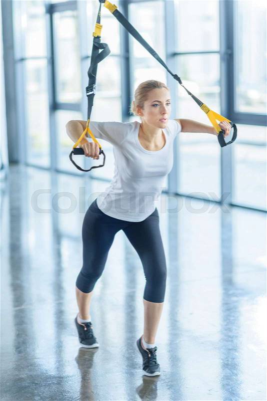 Concentrated sportswoman training with resistance band in sports center, stock photo