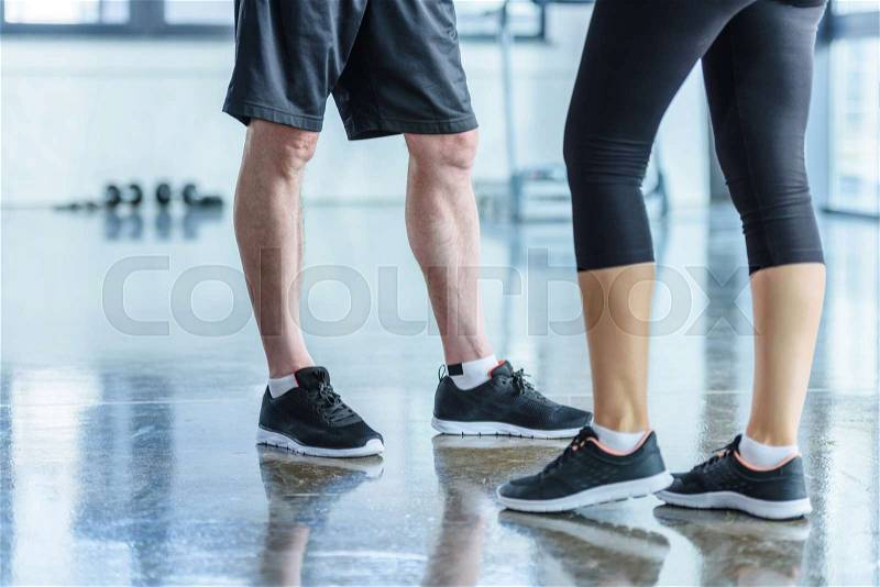Low section view of sportswoman and sportsman standing in sports center, stock photo