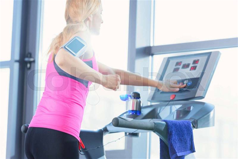 Low angle view of sporty blonde woman exercising on treadmill in gym , stock photo