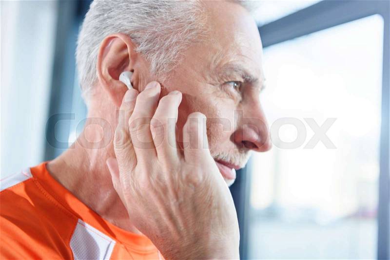 Close-up profile portrait of bearded mature man in earphones looking away, stock photo