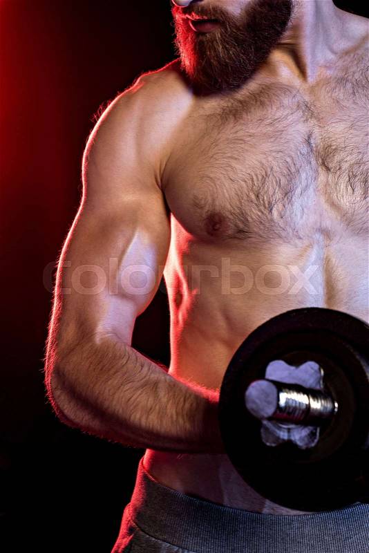 Bodybuilder training with dumbbell isolated on black with dramatic lighting, stock photo