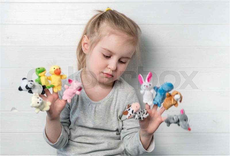 Lovely sad small girl with doll puppets on her hands, smiling and playing, stock photo