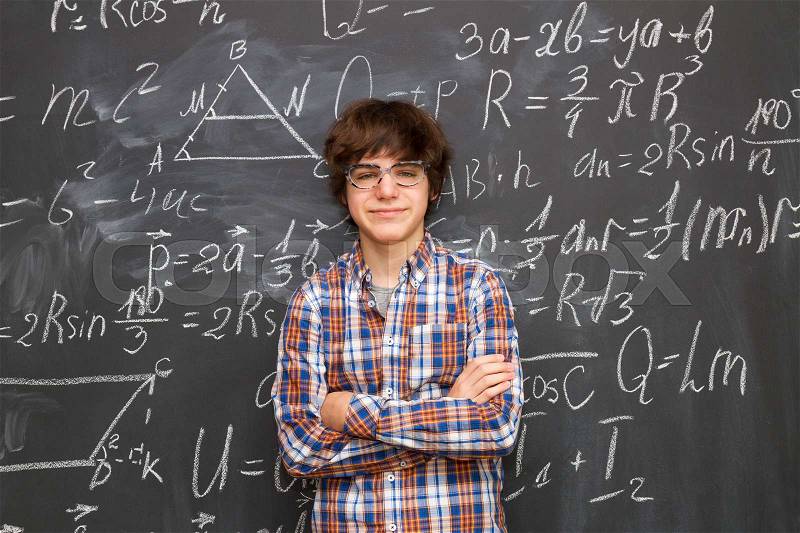 Teen Boy in glasses, blackboard filled with math formulas background, stock photo