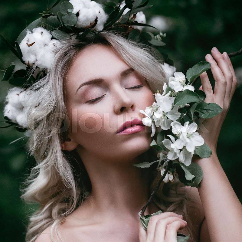 Spring Model Girl with White Apple Blossoms. Beautiful Woman with Healthy Skin and Flower Wreath Outdoors, stock photo