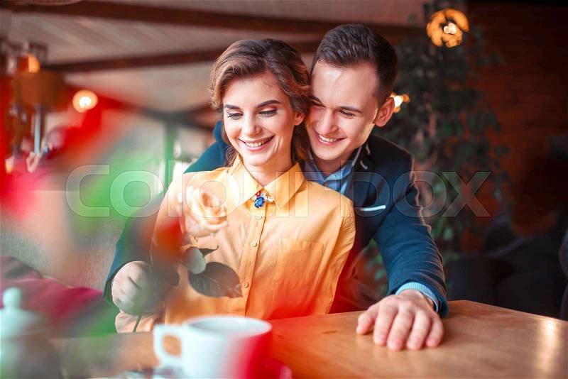 Happy man in suit gives rose to beautiful woman, romantic date in restaurant. Beautiful relationship of love couple, stock photo