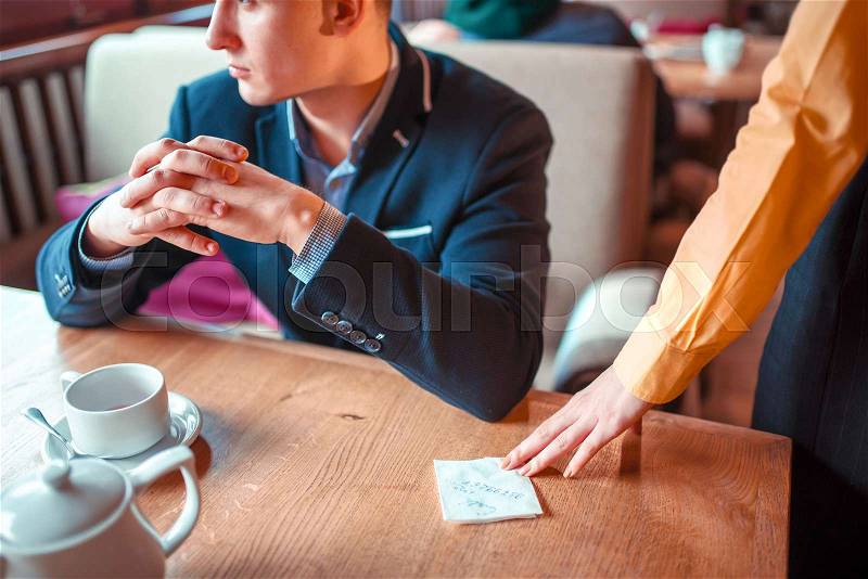Female person hands gives to man a love note with a phone number closeup view. Attractive proposal, stock photo