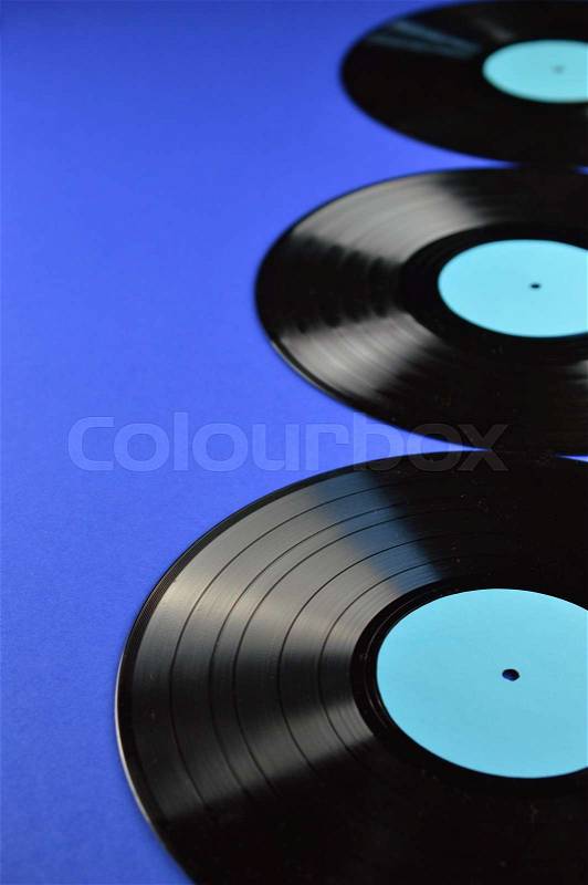 Drei alte schwarze Vinylschallplatten mit leerem, türkisfarbenem Etikett auf blauem Hintergrund, stock photo