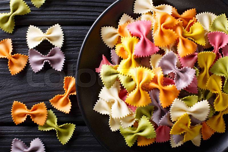 Italian natural colored farfalle pasta close-up on a plate on a black table. Horizontal view from above , stock photo