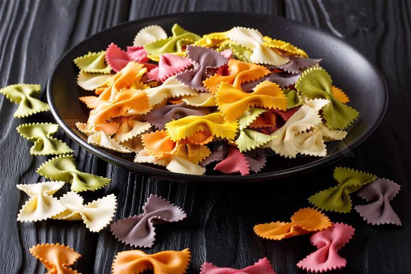 Italian natural colored farfalle pasta close-up on a plate on a black table. horizontal , stock photo