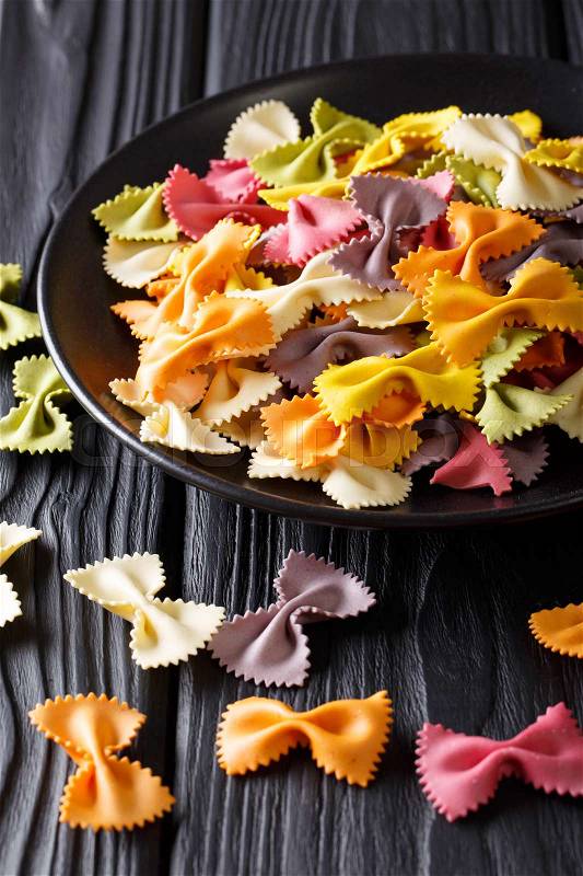 Italian dry colored farfalle pasta closeup on a plate on a table. Vertical , stock photo