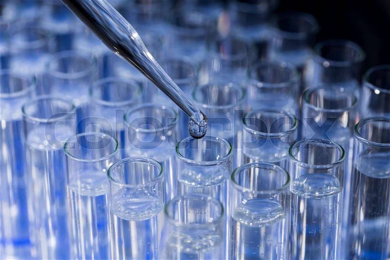 Laboratory glassware with pipette dropping fluid into test tube, stock photo