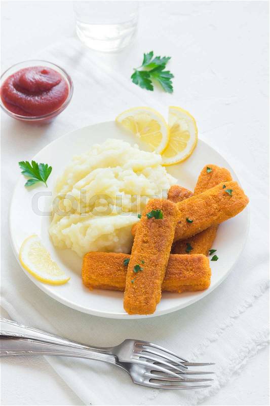 Fried fish fingers, mashed potatoes, tomato sauce and lemon. Delicious lunch with fish sticks and vegetables, convenient seafood, stock photo