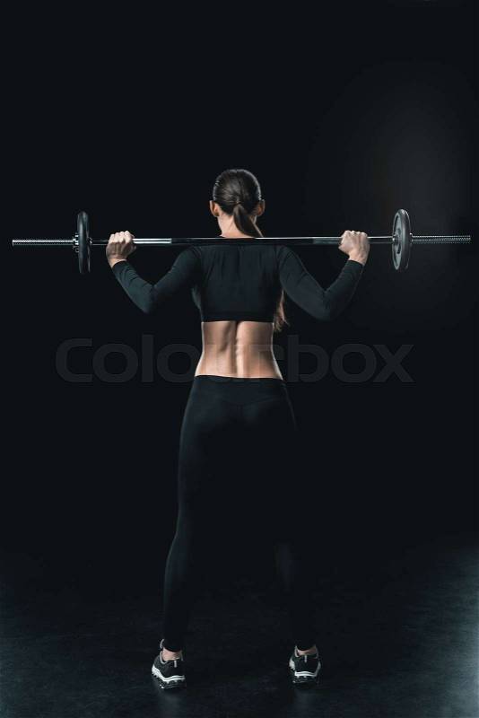 Young fitness woman training with barbell isolated on black. , stock photo