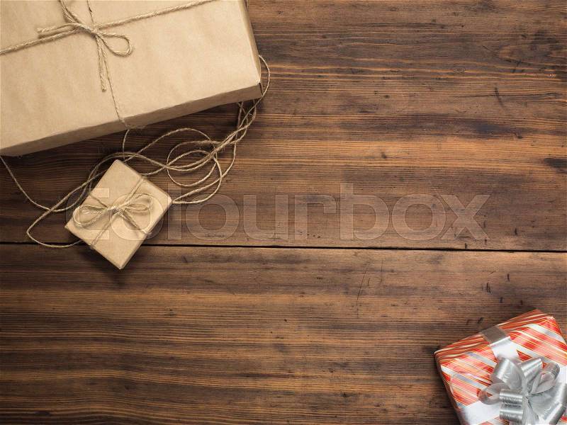 Boxes in craft paper, eco paper on the wooden table. Top view. Parcels or gifts tied with twine. Brown paper wrapped gift box with rope bow on a old rustic wood background. Background for your design, stock photo