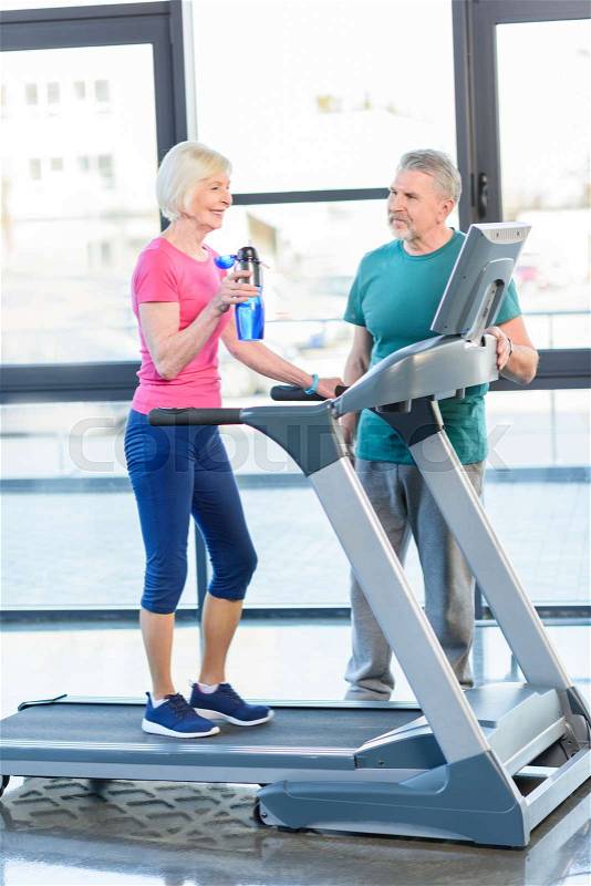 Old sport couple training on treadmill in fitness class for senior people , stock photo
