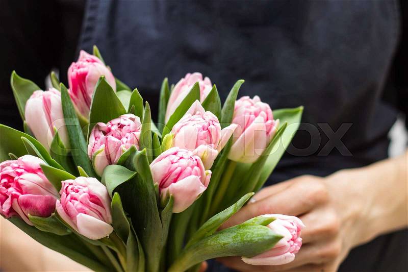 Close-up of vivid bouquet at florist's hands. Bouquet of pink tulips, stock photo