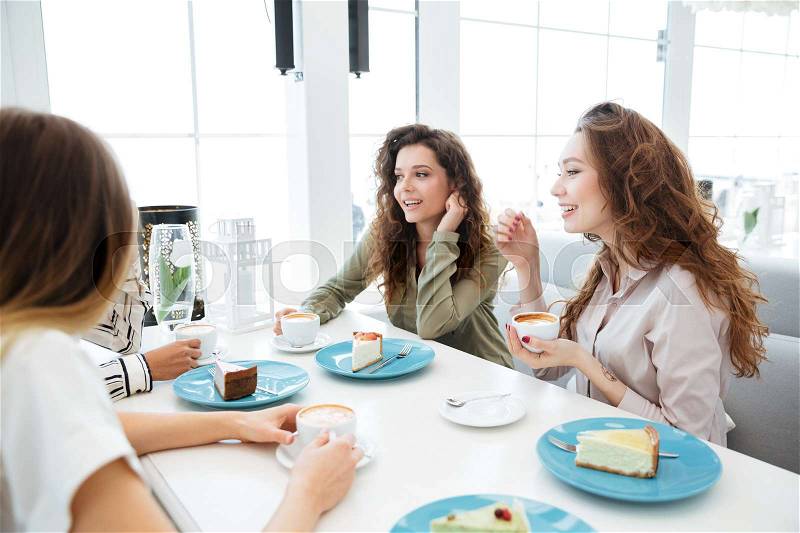 Side cropped view of four women which talking and sitting by the table in cafe, stock photo