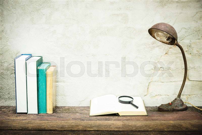 Closeup of workplace with open book stationery items and retro lamp on wooden table with white concrete background. Vintage filtered. Education concept. Reading and researching concept, stock photo
