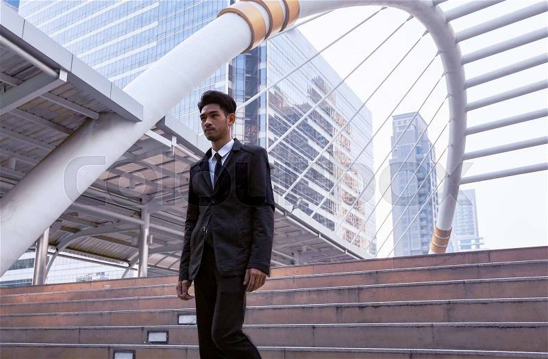 Confident businessman going down and walking on stairs, stock photo