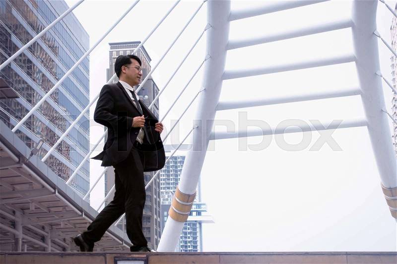 Confident businessman going down and walking on stairs and modern office building background, stock photo