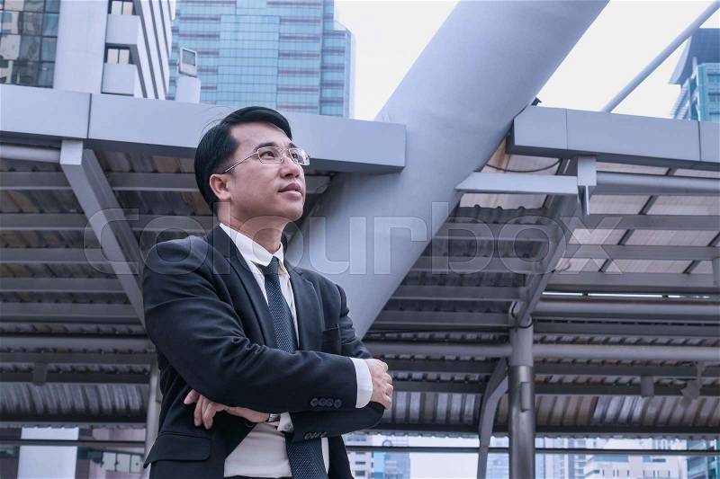 Confident Asian Businessman standing and looking at city for vision concept, stock photo