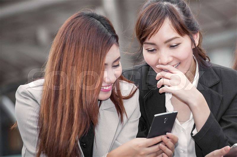 Asian business woman happy to use cell phone with colleague and discussion topic on business conceptual, stock photo