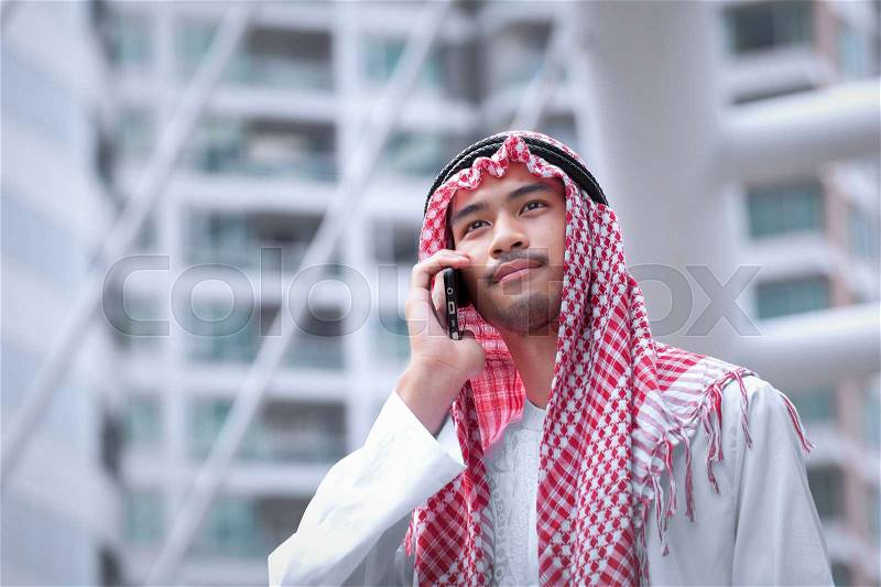 Arabian businessman using cell phone and modern business city background, stock photo