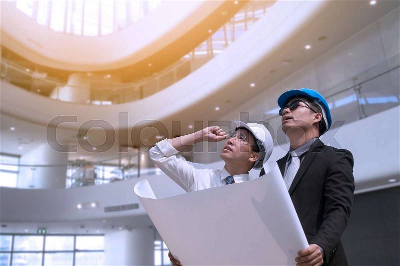 Asian businessman and engineer architect professional occupation corporate city looking away and holding construction industrial plan for working concept, stock photo