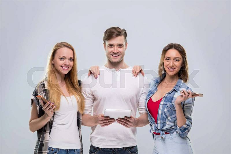 Casual People Group, Young Man Two Woman Happy Smile Using Cell Smart Phone Network Communication Over Grey Background, stock photo
