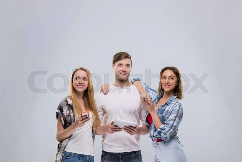 Casual People Group, Young Man Two Woman Happy Smile Using Cell Smart Phone Network Communication Looking To Copy Space Over Grey Background, stock photo