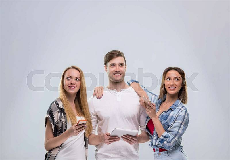 Casual People Group, Young Man Two Woman Happy Smile Using Cell Smart Phone Network Communication Looking To Copy Space Over Grey Background, stock photo