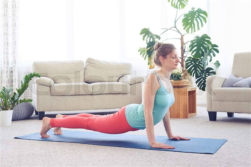 Wide shot of charming lady doing upward-facing dog pose standing toes, stock photo