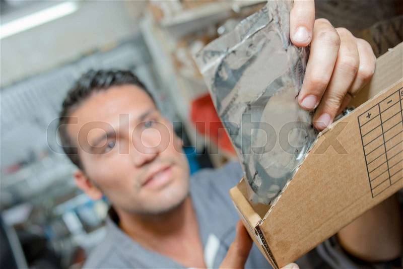 Mechanic getting gasket from box of spares, stock photo