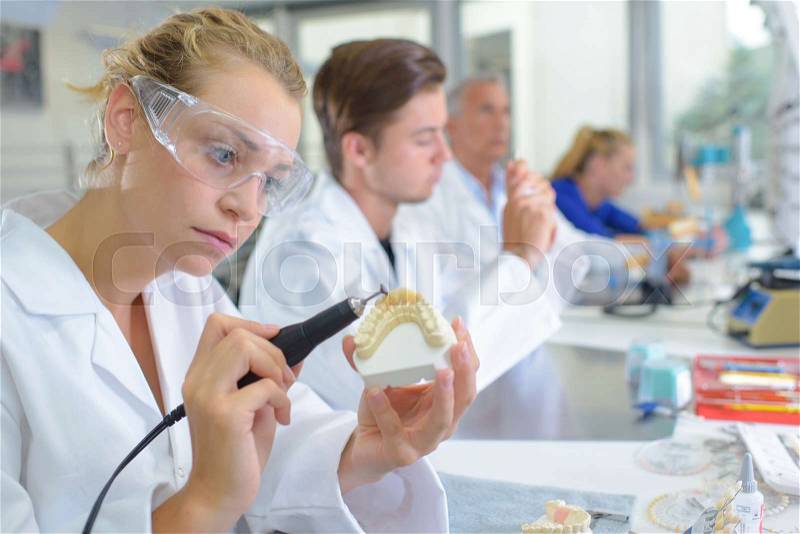 Dental technician grinding tooth, stock photo