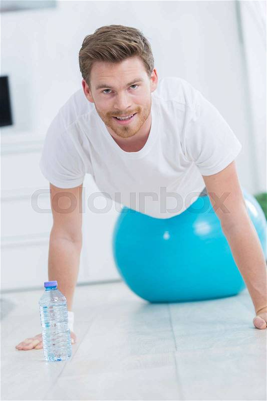 Sporty man doing push ups exercises on the gym ball, stock photo