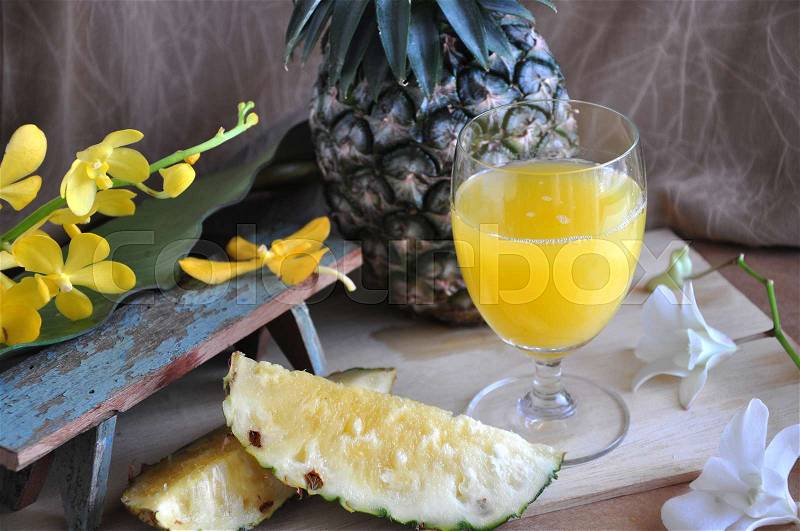 Glass of pineapple juice with fresh pineapple on wooden board, stock photo