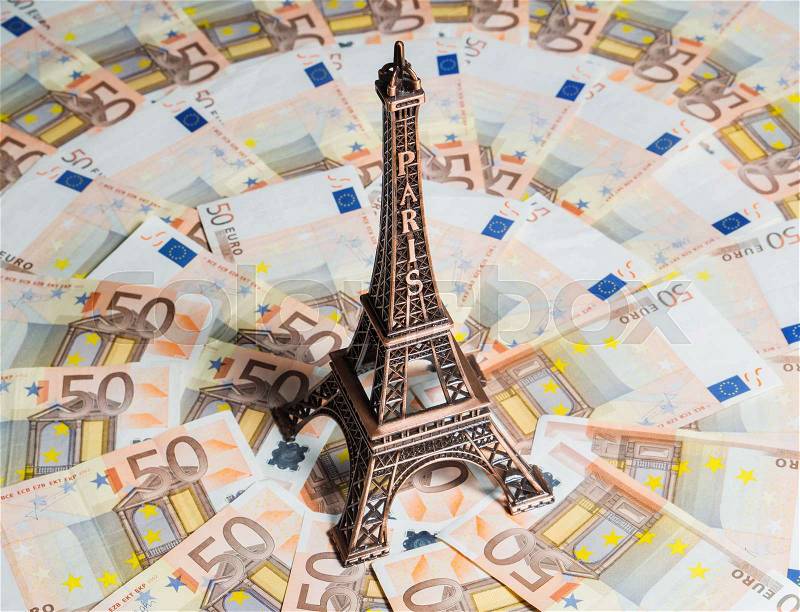 Eiffel Tower souvenir surrounded by vacation money. A lot of euro bills. Travel budget concept, stock photo