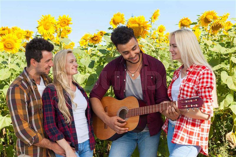 Young people listening guy playing guitar friends drinking beer bottles outdoor countryside, two couple standing near car happy smile summer sunflower, stock photo