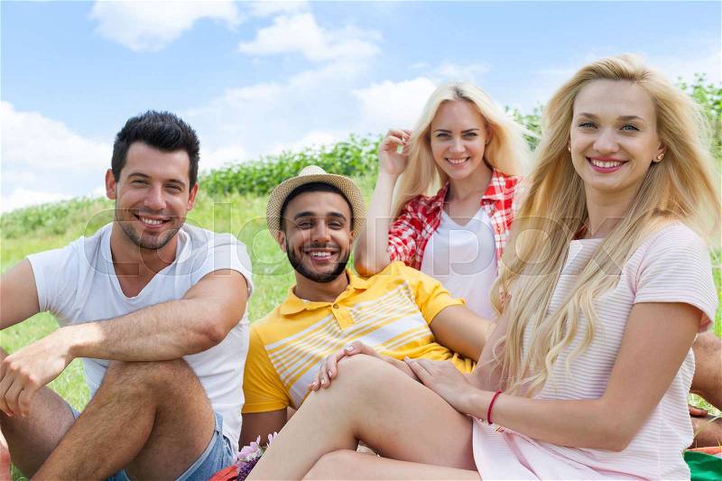 Friends picnic people group sitting blanket outdoor green grass two couple summer sunny day blue sky, stock photo