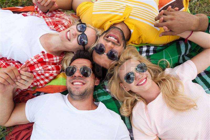 Happy people group young friends lying down on picnic blanket outdoor, two couple summer sunny day smile top angle view, stock photo