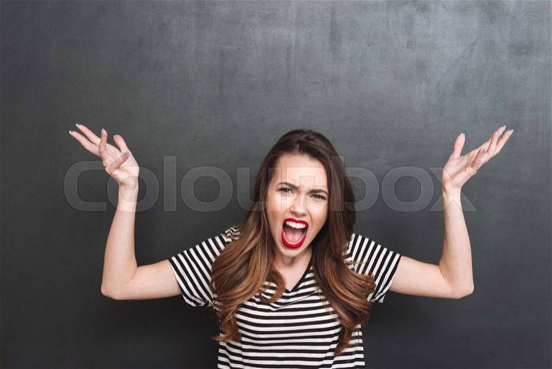 Uncomprehending screaming woman looking at the camera over black background, stock photo