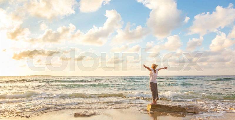 Relaxed woman enjoying sun, freedom and life an beautiful beach in sunset. Young lady feeling free, relaxed and happy. Concept of vacations, freedom, happiness, enjoyment and well being, stock photo