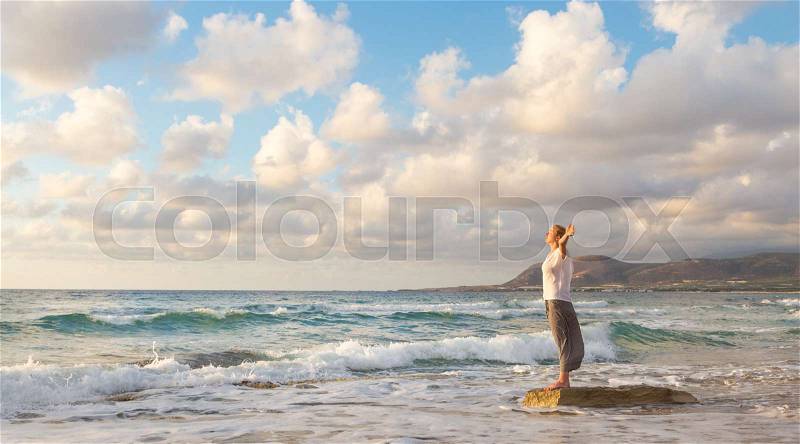 Relaxed woman enjoying sun, freedom and life an beautiful beach in sunset. Young lady feeling free, relaxed and happy. Concept of vacations, freedom, happiness, enjoyment and well being, stock photo