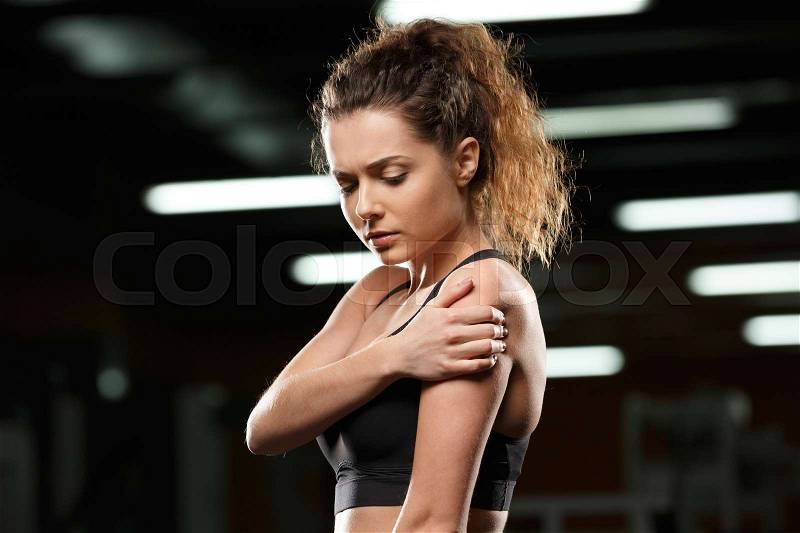Picture of serious sports lady standing and posing in gym and looking aside, stock photo