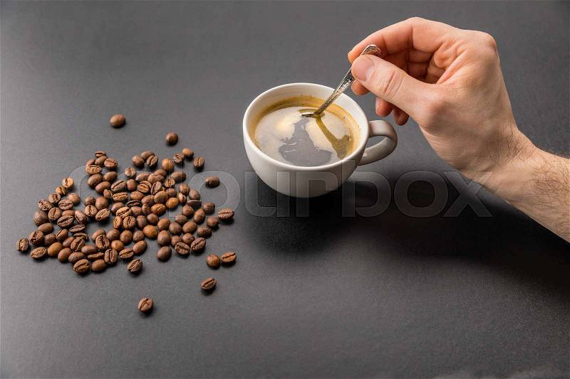 Close-up partial view of person mixing hot coffee with spoon, stock photo
