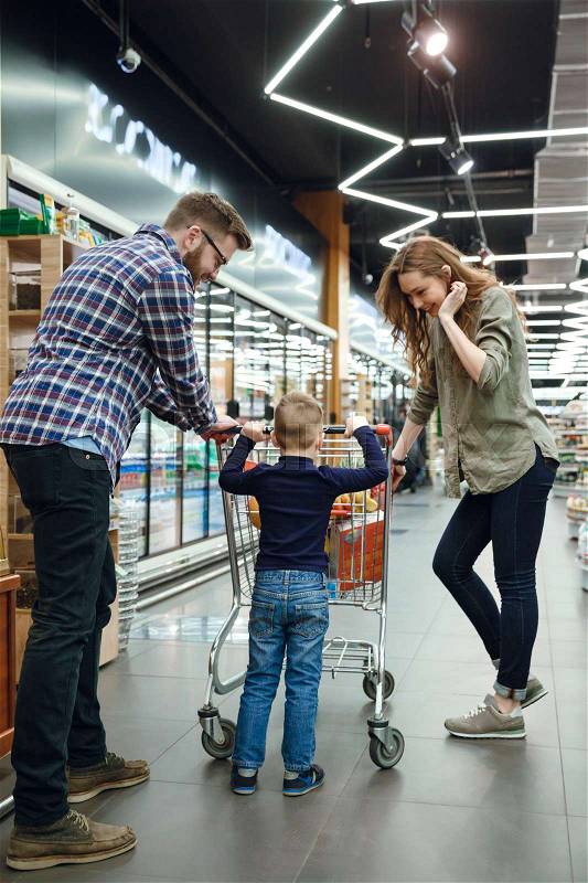 Back view of a happy family in supermarket. Vertical image, stock photo